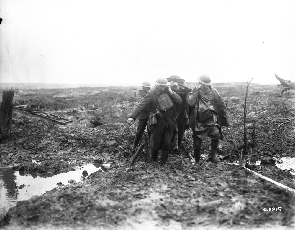 Casualties: Stretcher bearers bringing in a wounded man over muddy ground at Passchendaele. Canadian wounded being brought through the mud. Battle of Passchendaele. November, 1917. MIKAN No. 3397040